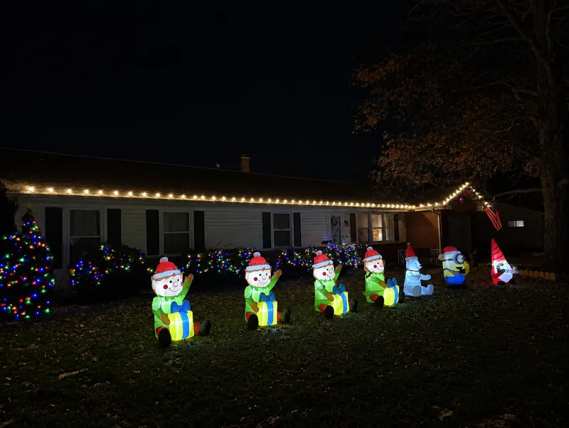 Ranch home with warm white roofline lights and yard decorations