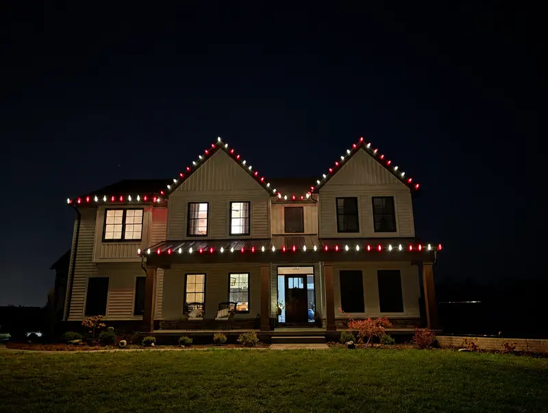 Two story home with white roofline lights and red lights along the porch